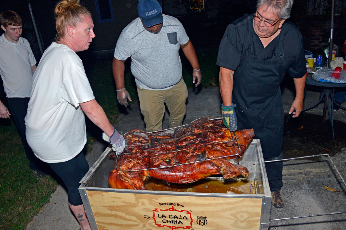 Removing cooked pig from Caja China