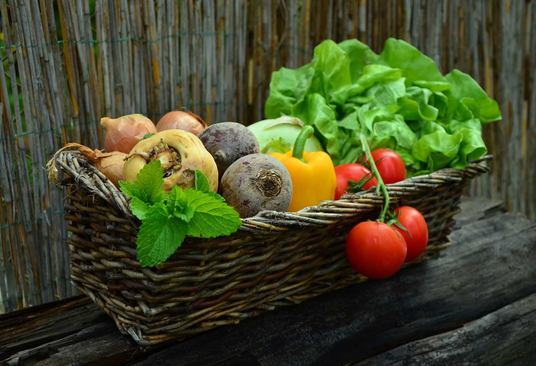 Assortment of vegetable types in basket. Root, fruiting, and leafy veg